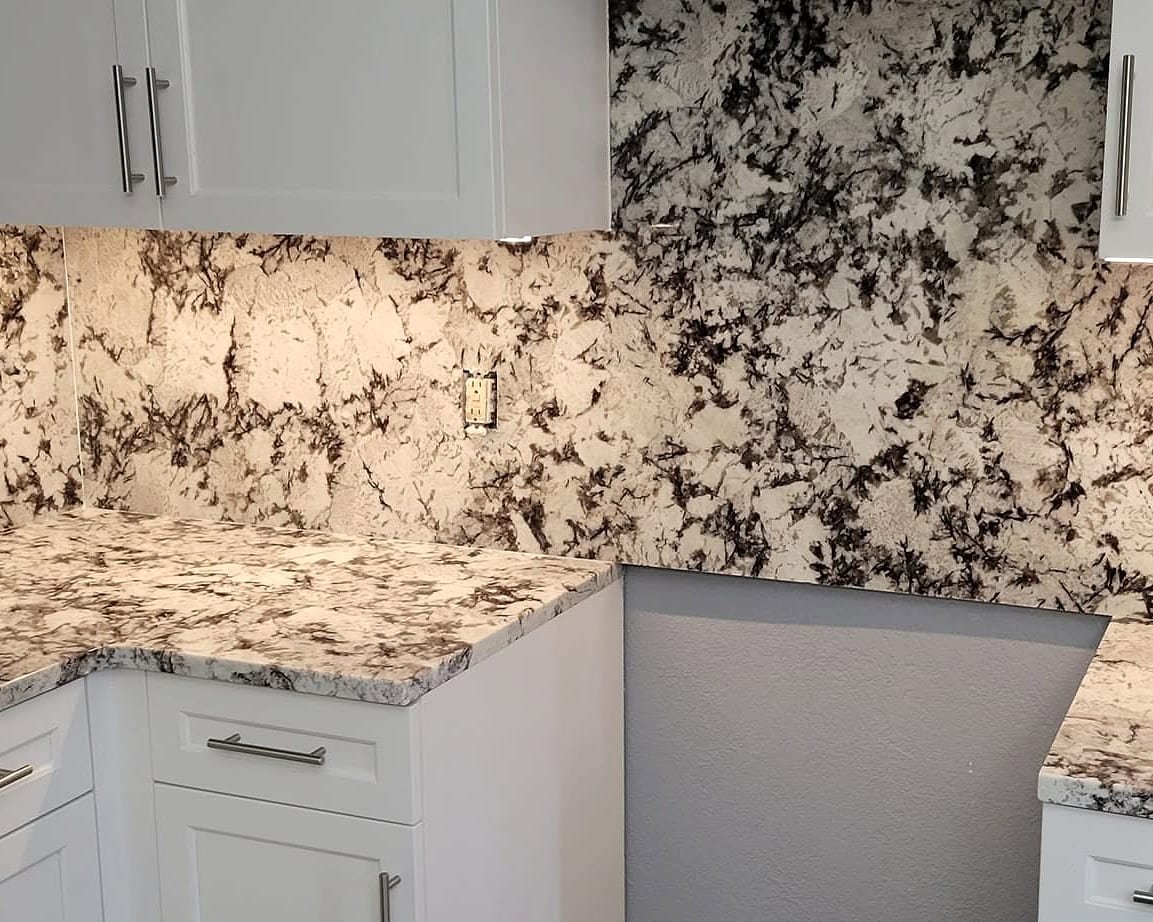 Fuzion granite installation with white and black granite countertops and a full-height granite backsplash under white cabinets