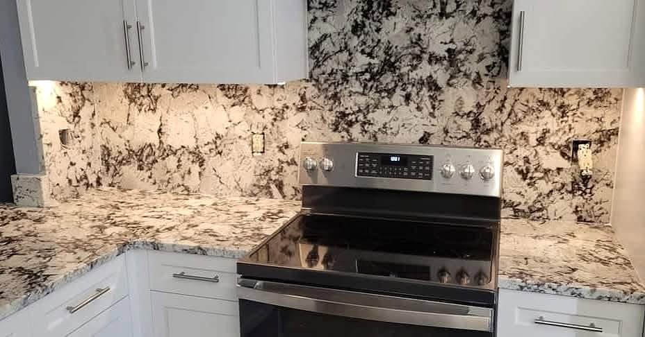 White and black granite countertops with a full-height granite backsplash behind an electric range