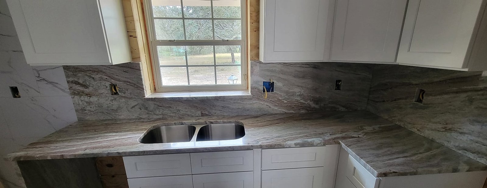 L-shaped kitchen with marble countertops, a double undermount sink and a full-height marble backsplash installed by Fuzion Stone Surfaces