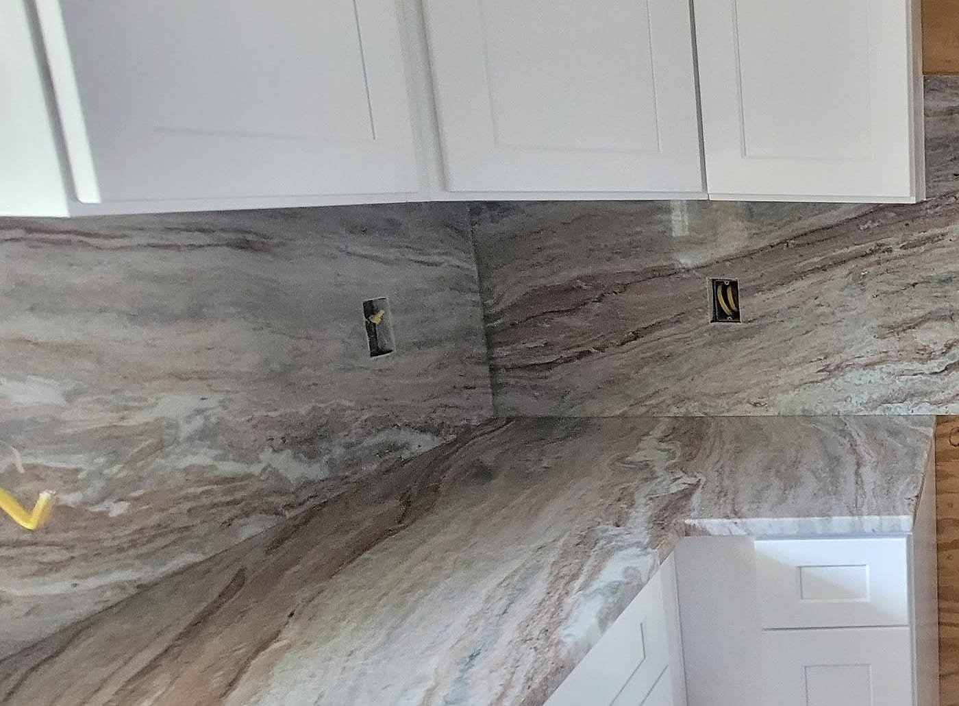 Marble countertop corner with a matching marble backsplash under white shaker cabinets