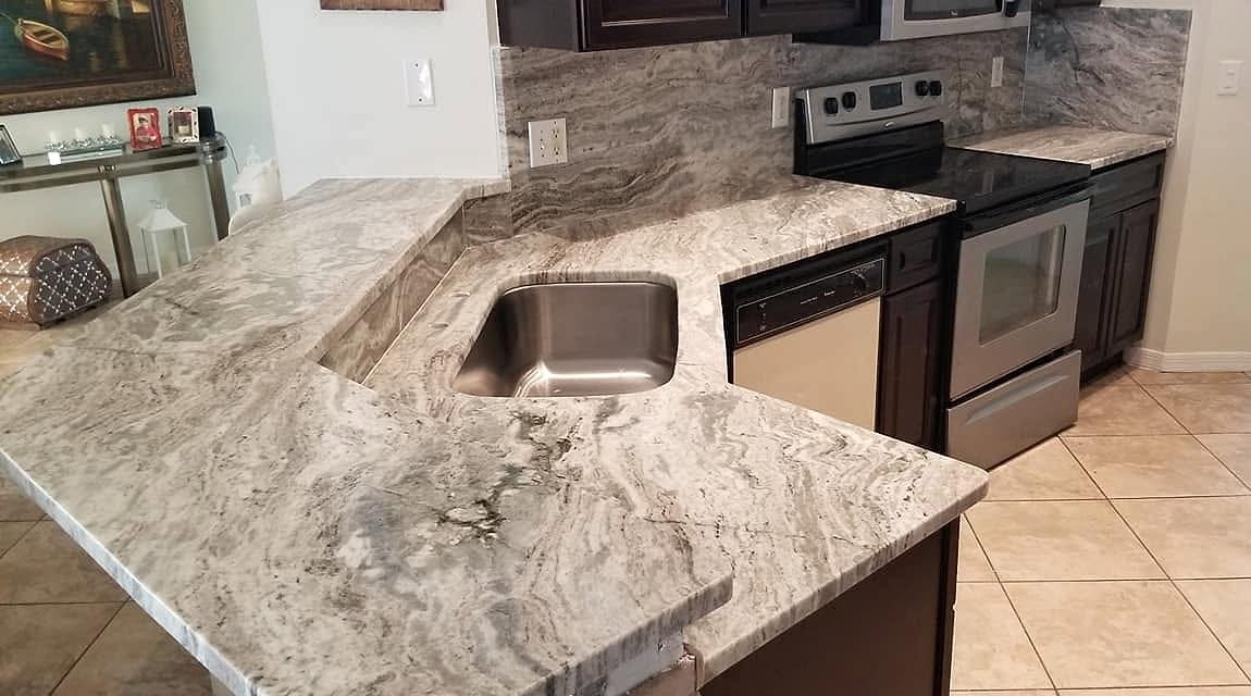 Kitchen with a raised marble bar, undermount sink and full-height marble backsplash installed by Fuzion Stone Surfaces